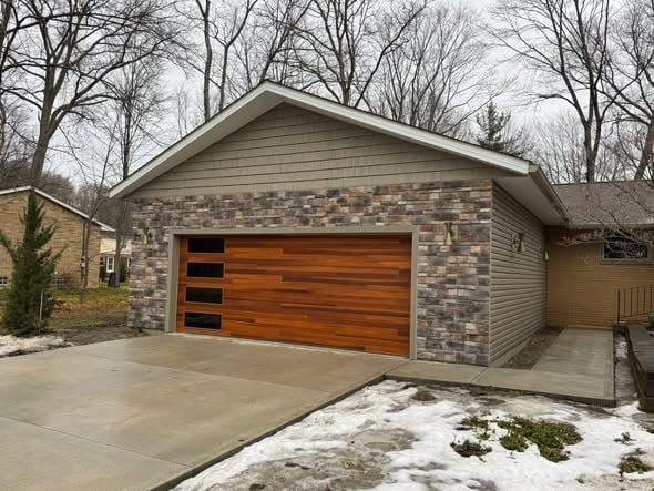 Two-car garage addition with wood-look garage door, cultured stone, and new driveway in Broadview Heights, Ohio