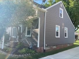 Side of a home with new charcoal-gray vinyl siding and gutters